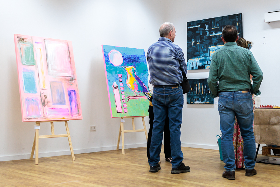 Three people looking at an artwork on a wall