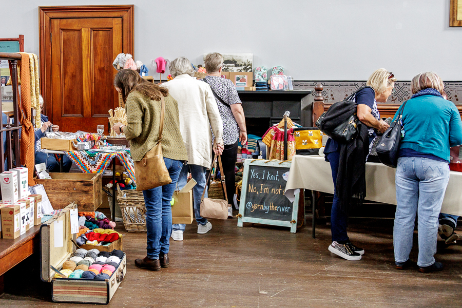 People looking at tables of goods at a fibre festival